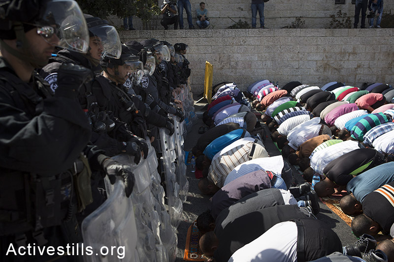 פלסטינים מתפללים לכיוון אל-אקסה תחת שמירה של כוחות מג״ב במהלך תפילת יום השישי, בשכונת ואדי אל-ג׳וז, מזרח ירושלים, 17 אוקטובר, 2014. (אקטיבסטילס)