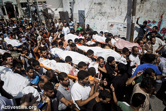 הלווייתם של 21 בני משפחת אלנג'אר שנהרגו זמן קצר לפני הפסקת אש, בכפר בני סוהילא, מזרחית לח'אן יונס, 26 ביולי, 2014. משפחת אלנג'אר ברחה מביתה בחוזעה, כמו רבים אחרים מכפרם, בעקבות כיבוש המקום ע״י הצבא הישראלי. כ-1000 פלסטינים נהרגו עד כה בעזה וכ-5000 נפצעו. (אן פאק/אקטיבסטילס)