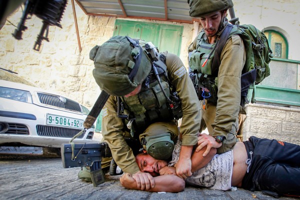 חיילים עוצרים פלסטיני במהלך פשיטות על בתים בחברון (ויסאם השלמון / פלאש90)