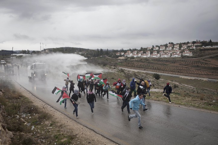 פעילים פלסטינים, בינלאומיים וישראלים בורחים מרכב "בואש" של הצבא במהלך הפגנה נגד הכיבוש בכפר נבי סאלח בגדה המערבית. 13 בינואר 2012 (אקטיבסטילס)