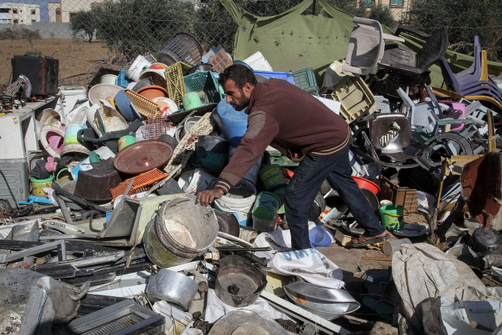 פלסטיני תושב עזה אוסף חפצים מהריסות ביתו שלא שוקמו מאז המלחמה לפני שנתיים. דצמבר 2016 (עבד רחים חטיב / פלא90)