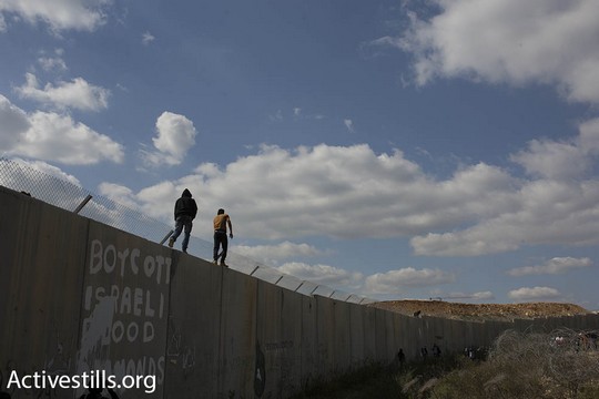 אני עומד על החומה. מפגינים במהלך הצעדה לציון 12 שנות מאבק עממי נגד החומה והכיבוש בבלעין (פאיז אבו-רמלה/אקטיבסטילס)
