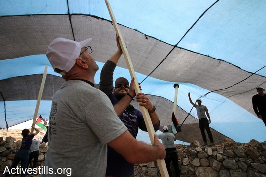 פעיל פלסטיני ופעיל יהודי אמריקאי מניחים קורות של אוהל. "צומוד, מחנה החירות". הכפר סארורה הגדה המערבית, 19 במאי 2017 (צילום: אחמד אל-באז אקטיבסטילס)