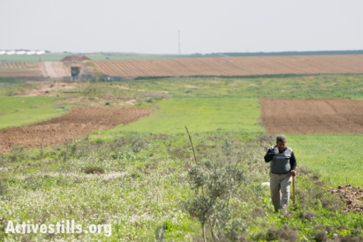חקלאי פלסטיני עובד בשדות הסמוכים לגבול המזרחי של עזה. עמדות הצבא הישראלי נראות מרחוק בצד שמאל (ראיין רודריק ביילר/אקטיבסטילס)