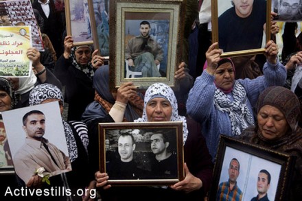 נשים פלסטיניות מציגות תמונות של קרוביהן - אסירים הכלואים בבתי כלא ישראליים. יום האסיר הפלסטיני, רמאללה, ה-17 באפריל, 2014 (אקטיבסטילס)