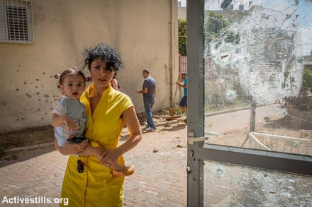 אישה ובנה התינוק עומדים באזור שנפגע ע״י טילים ששוגרו מרצועת עזה, שדרות, 15 ביולי 2014. (יותם רונן/אקטיבסטילס)