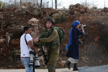עלא בדרנא וחייל בצומת תפוח. ברקע: צלמת ישראלית פועלת ללא הפרעה (איימן נובאני)