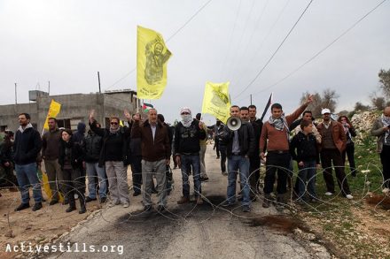 מפגינים ניצבים מאחורי גדר תיל שנפרסה בכביש על ידי הצבא בזמן הפגנה נגד הכיבוש וההתנחלויות בכפר קדום 30 בדצמבר 2011 (אקטיבסטילס)