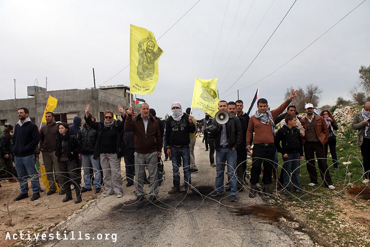 מפגינים ניצבים מאחורי גדר תיל שנפרסה בכביש על ידי הצבא בזמן הפגנה נגד הכיבוש וההתנחלויות בכפר קדום 30 בדצמבר 2011 (אקטיבסטילס)