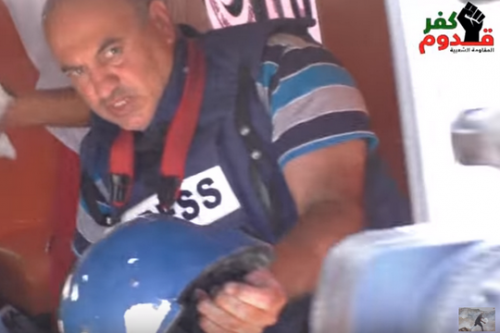 נידאל שתייה באמבולנס לאחר שנפגע מרימון הגז. בידו הקסדה שנפגעה (צילום מסך מהיו-טוב של כפר קדום)