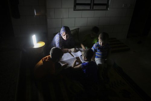 ילדים מכינים שיעורי בית לאור תאורת חירום בהפסקת החשמל הקבועה של עזה. מאי 2016 (עבד רחים חטיב / פלאש90)