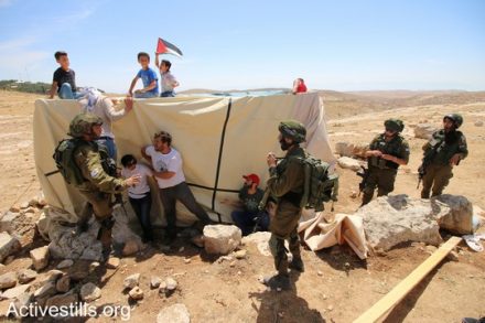 פעילים מנסים למנוע מחיילים לפרק את אחד מאוהלי המאחז במהלך הפלישה השניה של הצבא למקום. "צומוד, מחנה החירות". הכפר סארורה הגדה המערבית, 25 במאי 2017 (צילום: אחמד אל-באז אקטיבסטילס)