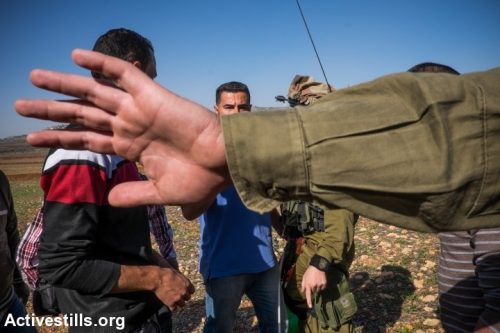 חייל מנסה לחסום צילום של פלסטינים (אילוסטרציה: אן פאק / אקטיבסטילס)