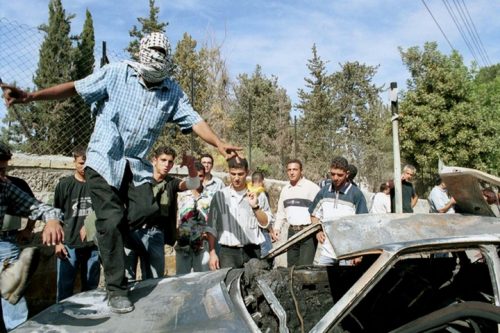 ואדים נורז'יץ ויוסי אברהמי נרצחו אחרי שמסרו את נשקם. זה פשע לפי החוק הבינלאומי. פלסטינים ליד המכונית השרופה של שני חיילי המילואים הישראלים (צילום: פלאש 90)